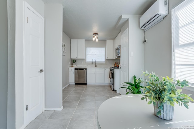 kitchen featuring sink, white cabinetry, a wall mounted air conditioner, a healthy amount of sunlight, and stainless steel appliances