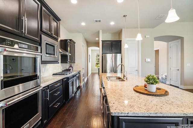 kitchen featuring a kitchen island with sink, sink, stainless steel appliances, and pendant lighting