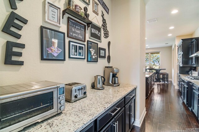 kitchen featuring dark hardwood / wood-style floors, light stone counters, and stainless steel appliances