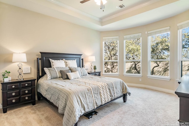 carpeted bedroom with a raised ceiling, ceiling fan, and crown molding