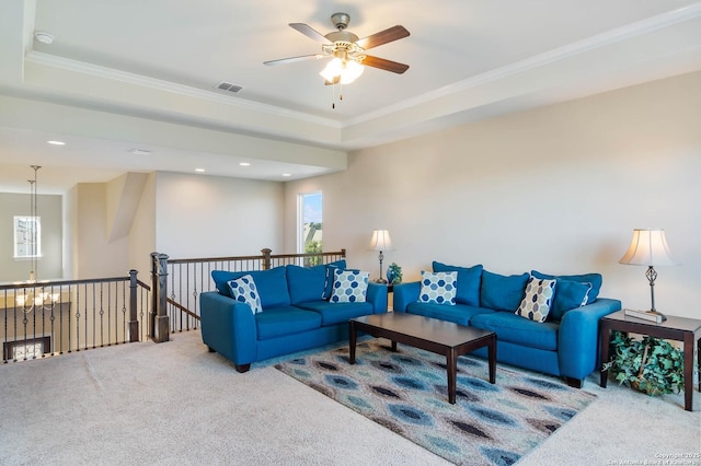 living room featuring carpet floors, ornamental molding, and a raised ceiling