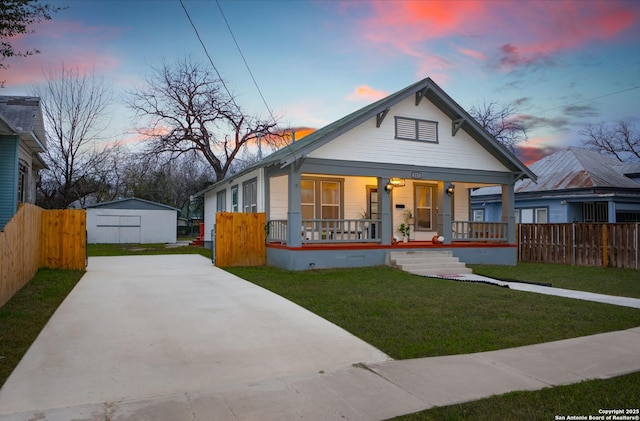 bungalow featuring covered porch, a yard, and an outdoor structure