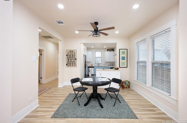 dining space with ceiling fan, sink, and light wood-type flooring