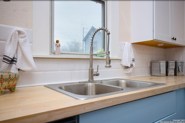 details featuring white cabinets, decorative backsplash, and sink