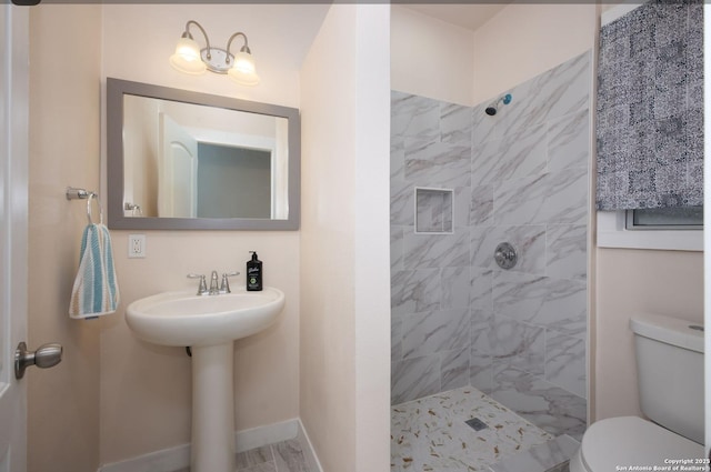 bathroom with toilet, tiled shower, and sink