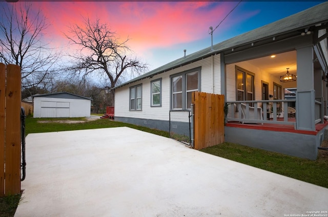 property exterior at dusk with a storage shed and a patio