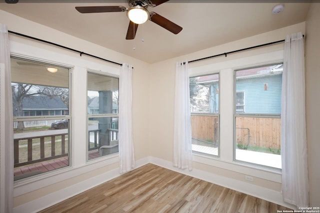 empty room featuring ceiling fan, a healthy amount of sunlight, and light wood-type flooring