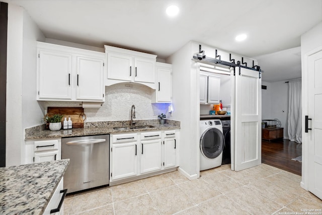 kitchen featuring stainless steel dishwasher, white cabinets, stone countertops, and sink