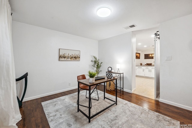 office area with dark hardwood / wood-style flooring and a barn door