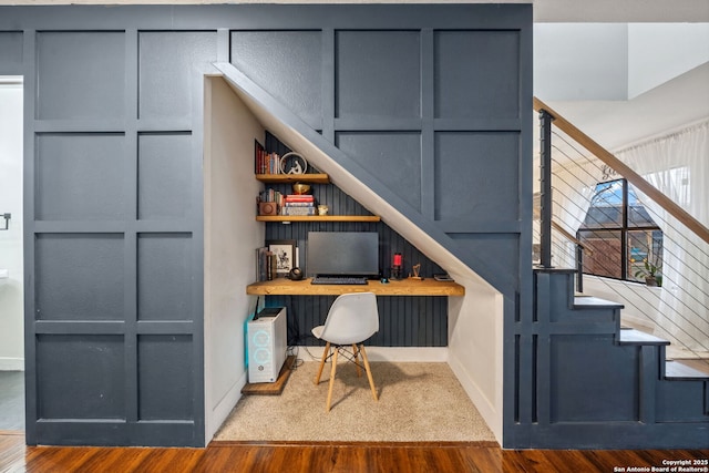 office area featuring built in desk, wood-type flooring, and built in features