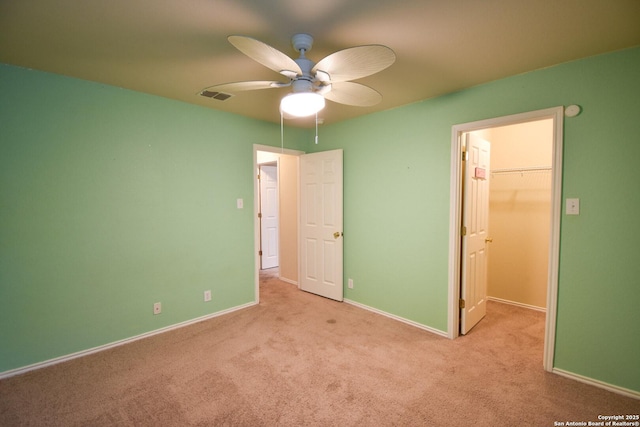 unfurnished bedroom with ceiling fan, light carpet, a closet, and a walk in closet