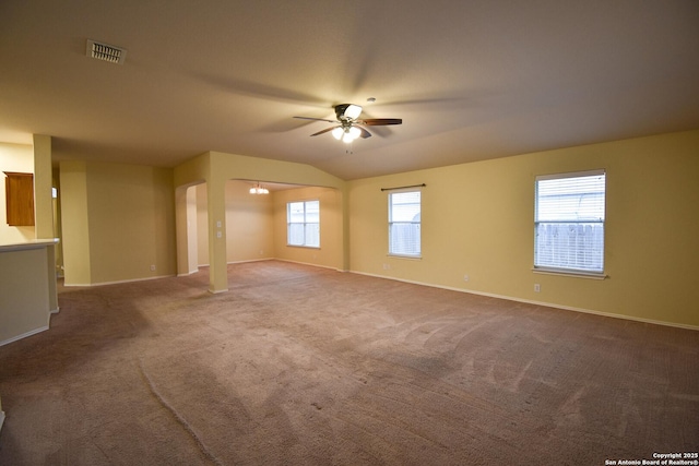 carpeted spare room with vaulted ceiling, ceiling fan, and plenty of natural light