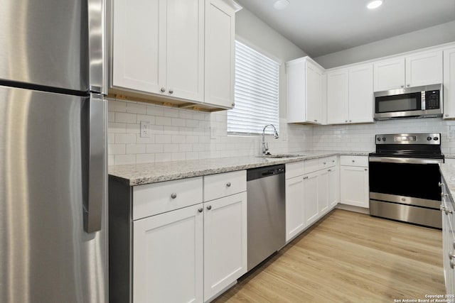 kitchen featuring light hardwood / wood-style floors, stainless steel appliances, white cabinets, light stone counters, and sink