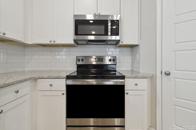 kitchen featuring decorative backsplash, light stone countertops, stainless steel appliances, and white cabinetry