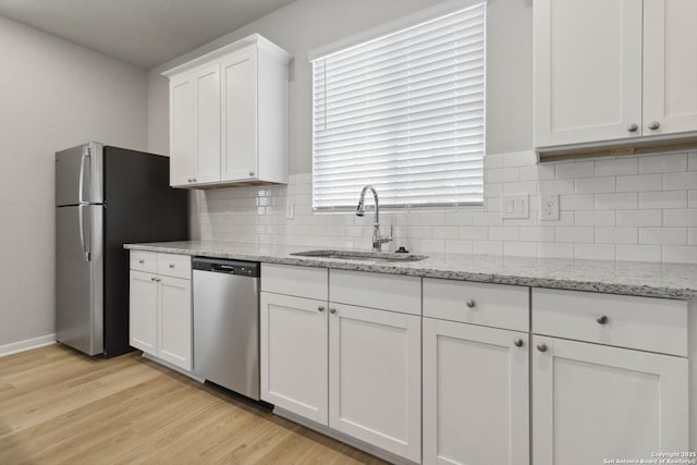 kitchen with light hardwood / wood-style floors, stainless steel appliances, light stone countertops, white cabinets, and sink