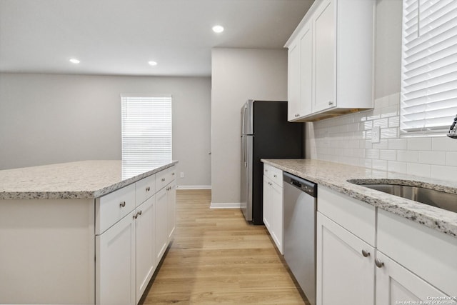 kitchen featuring tasteful backsplash, light hardwood / wood-style floors, sink, white cabinetry, and stainless steel appliances