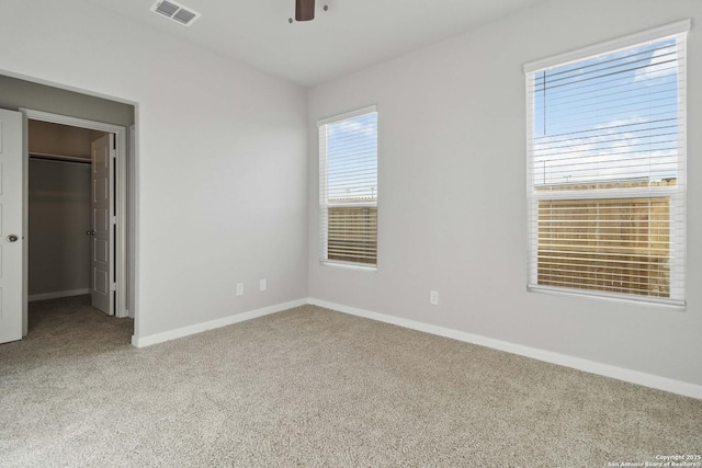 unfurnished bedroom with ceiling fan, light colored carpet, a closet, and a walk in closet