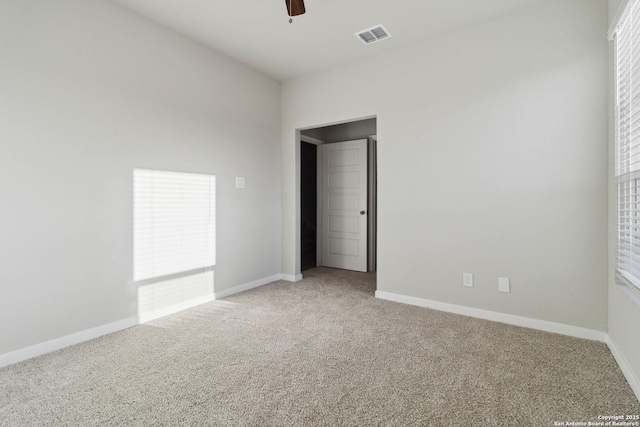 empty room with ceiling fan, a healthy amount of sunlight, and carpet flooring