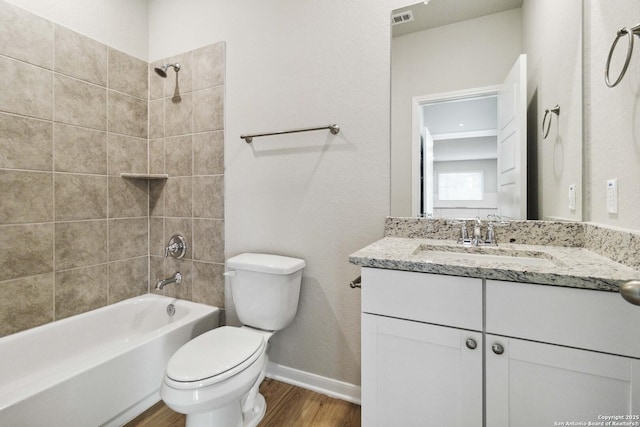 full bathroom with toilet, tiled shower / bath, hardwood / wood-style floors, and vanity