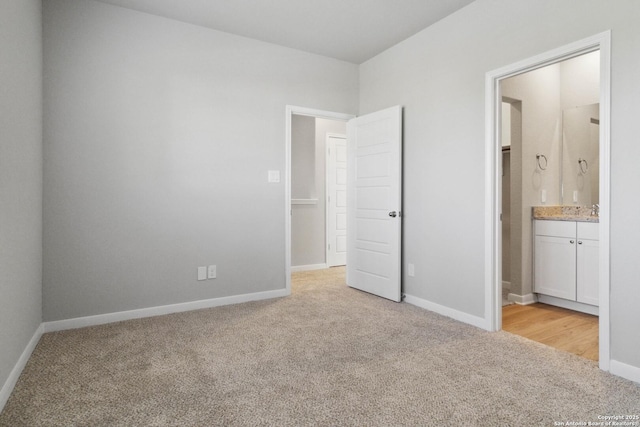 unfurnished bedroom featuring light colored carpet, sink, and ensuite bath