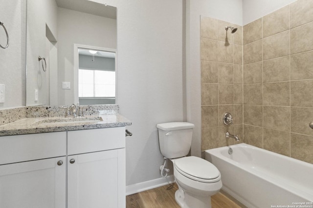 full bathroom with toilet, tiled shower / bath combo, wood-type flooring, and vanity