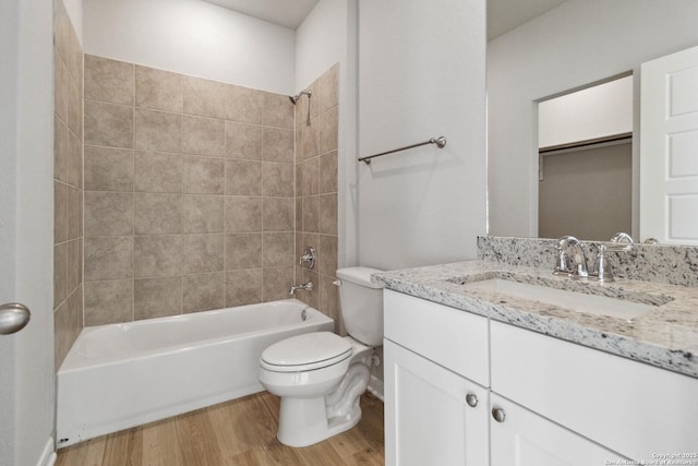 full bathroom featuring toilet, tiled shower / bath combo, hardwood / wood-style flooring, and vanity