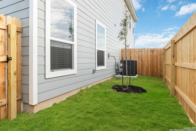 view of side of property featuring central AC unit and a yard