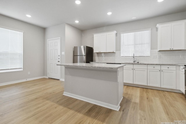 kitchen featuring white cabinets, backsplash, stainless steel fridge, and a center island