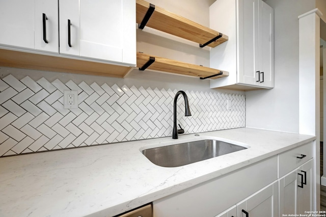 kitchen with light stone counters, sink, white cabinets, and tasteful backsplash