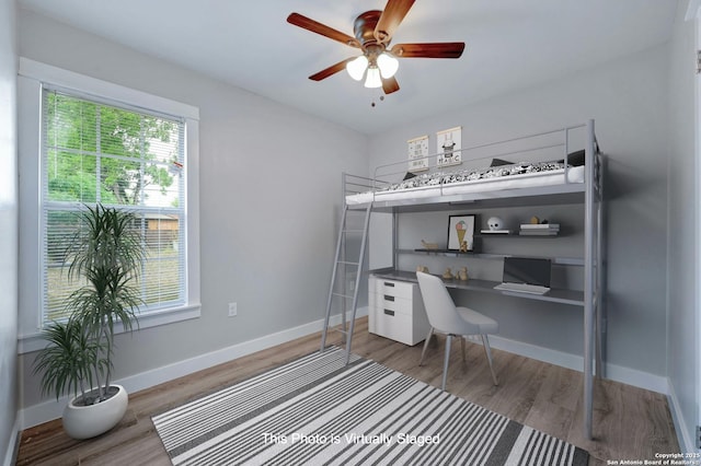 bedroom featuring hardwood / wood-style flooring, built in desk, and ceiling fan