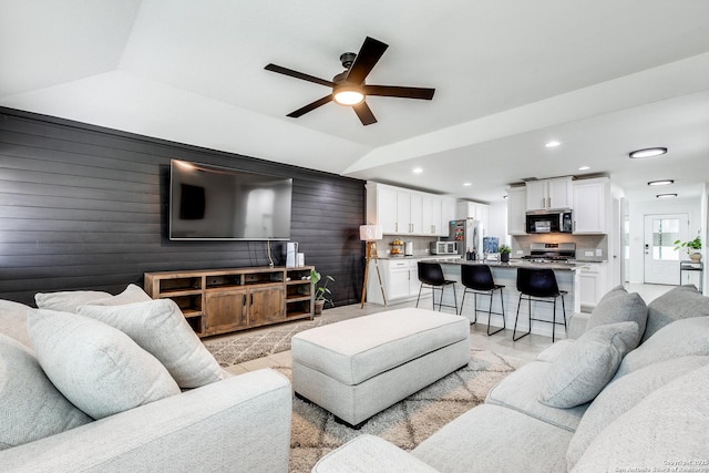 living room featuring lofted ceiling, ceiling fan, and wooden walls