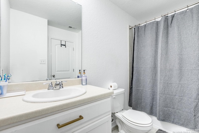 bathroom with a textured ceiling, toilet, and vanity