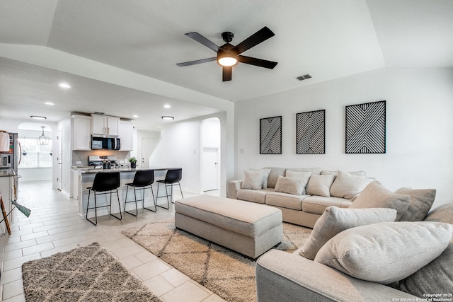 tiled living room with ceiling fan and lofted ceiling