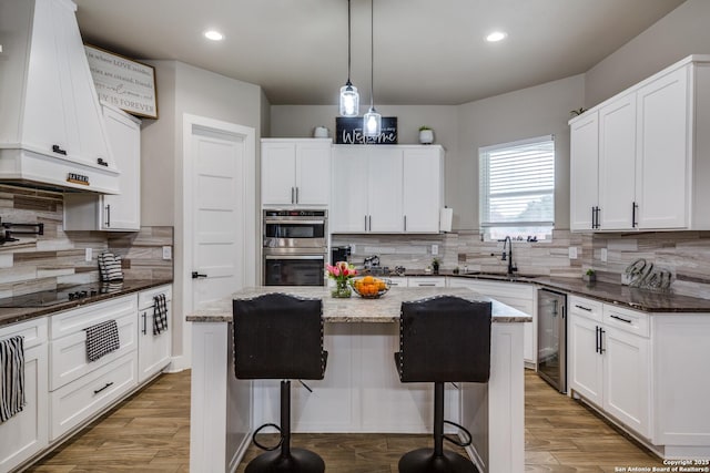 kitchen featuring sink, white cabinets, a center island, and dark stone countertops