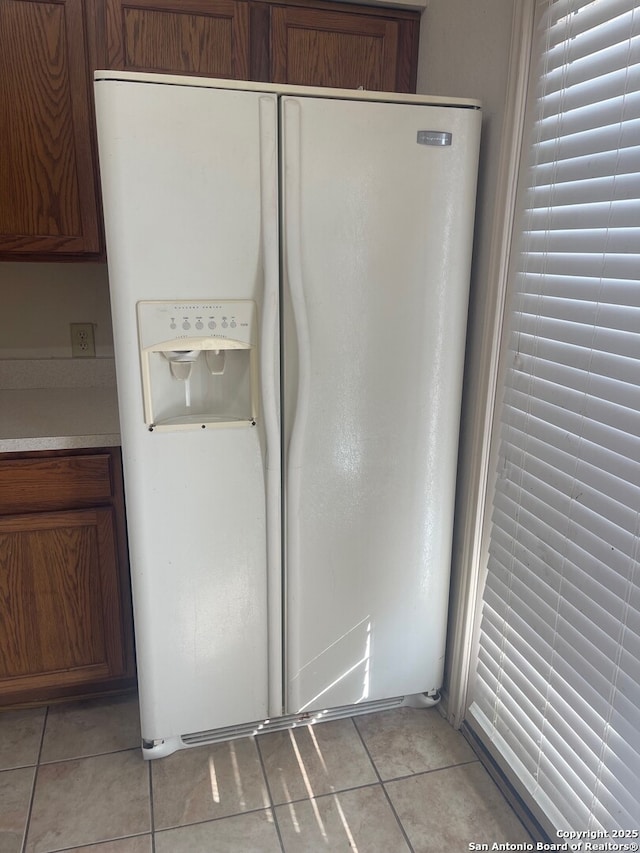 kitchen featuring light tile patterned floors and white refrigerator with ice dispenser