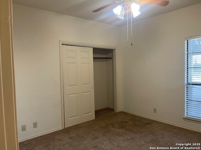 unfurnished bedroom featuring ceiling fan, a closet, and dark colored carpet