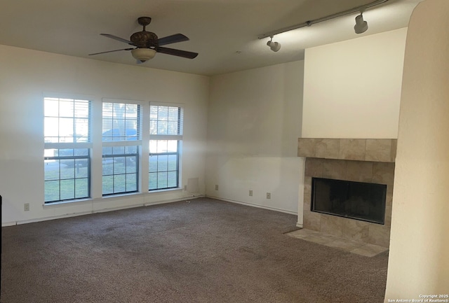 unfurnished living room featuring carpet, ceiling fan, a tile fireplace, and rail lighting