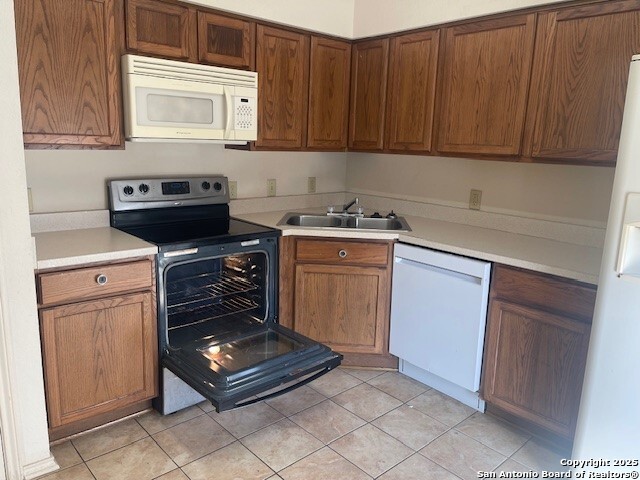 kitchen with light tile patterned flooring, sink, and white appliances