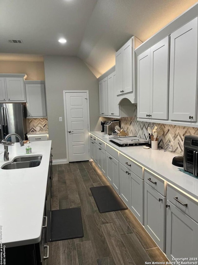 kitchen featuring white cabinetry, sink, backsplash, and stainless steel refrigerator