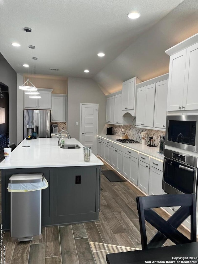 kitchen with white cabinetry, appliances with stainless steel finishes, an island with sink, and hanging light fixtures