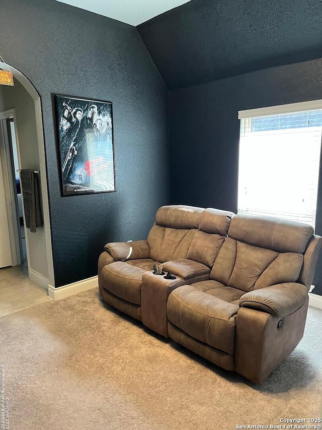 carpeted home theater featuring vaulted ceiling