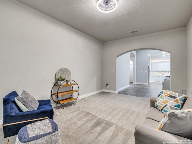 sitting room with a textured ceiling and carpet flooring