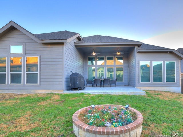 rear view of property featuring ceiling fan, a yard, and a patio area