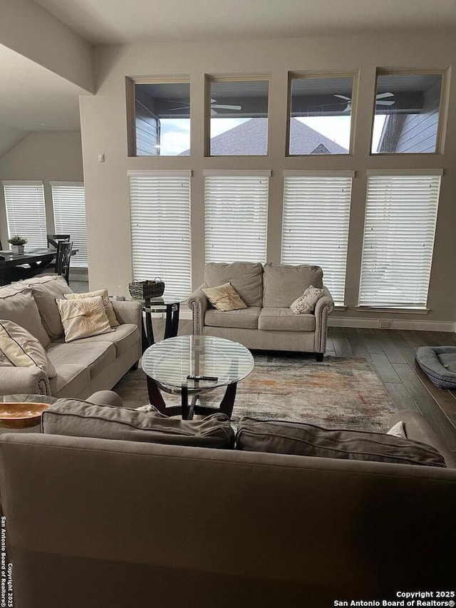 living room featuring a wealth of natural light, wood-type flooring, and vaulted ceiling