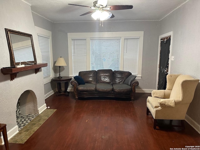 living room featuring ceiling fan, dark hardwood / wood-style floors, and a textured ceiling