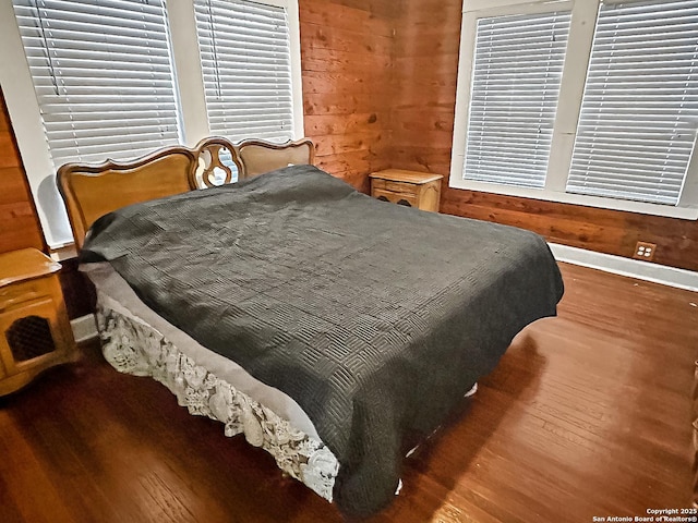 bedroom with hardwood / wood-style floors and wooden walls