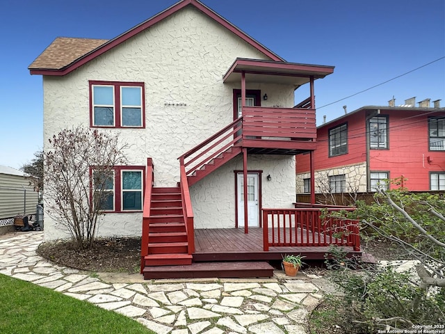 back of house with a wooden deck and a balcony