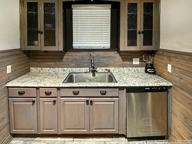 bar with light stone countertops, stainless steel dishwasher, wooden walls, and sink