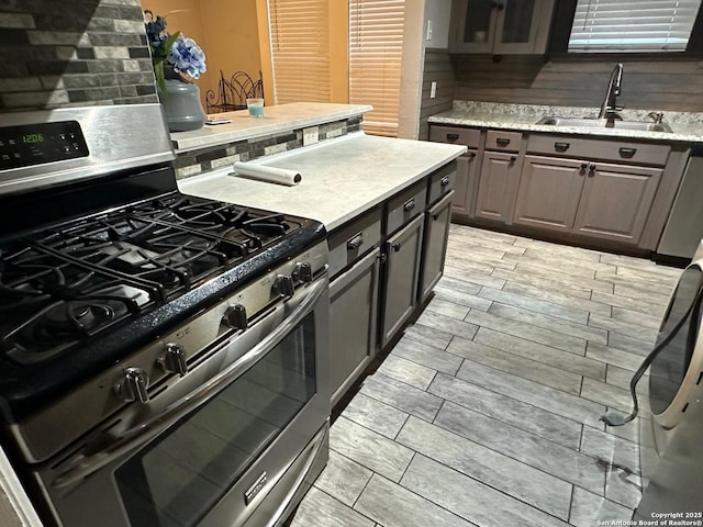 kitchen with sink, backsplash, and stainless steel range with gas cooktop