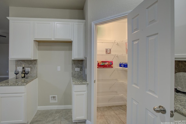 interior space with decorative backsplash, light stone counters, white cabinetry, and light tile patterned flooring